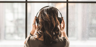A woman listens to a podcast while looking outside a window