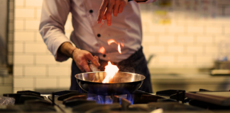 A chef in a kitchen cooking with a pan